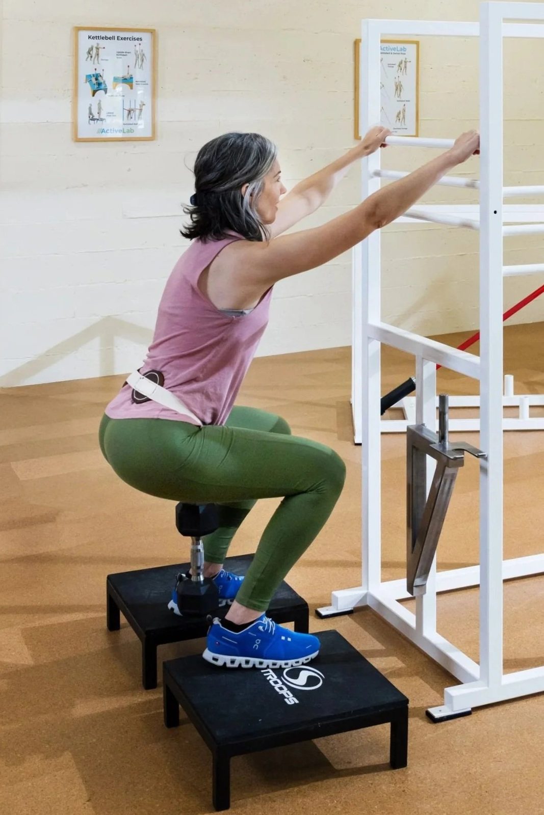 An older woman in athletic attire doing Squats Weightlifting with exercise equipment at ActiveLab in Vancouver, WA